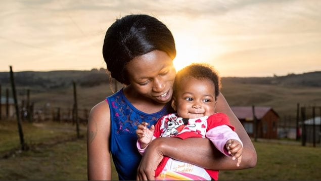 Woman holds a smiling baby. Learn about CDC's work to eliminate HIV and tuberculosis