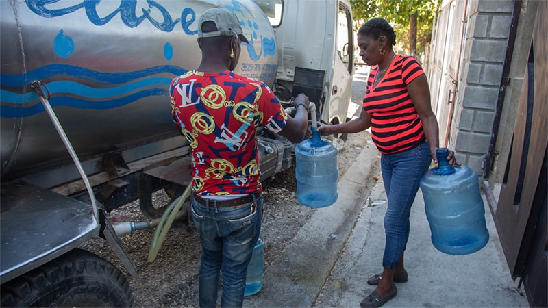 A worker fills water containers from a mobile tanker that provides clean drinking water to families in Haiti’s capital.