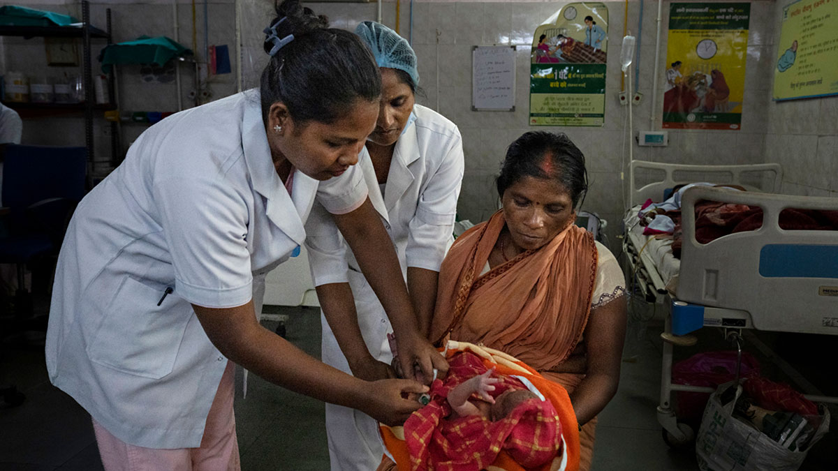 A health professional vaccinates a newborn while the mother holds the baby