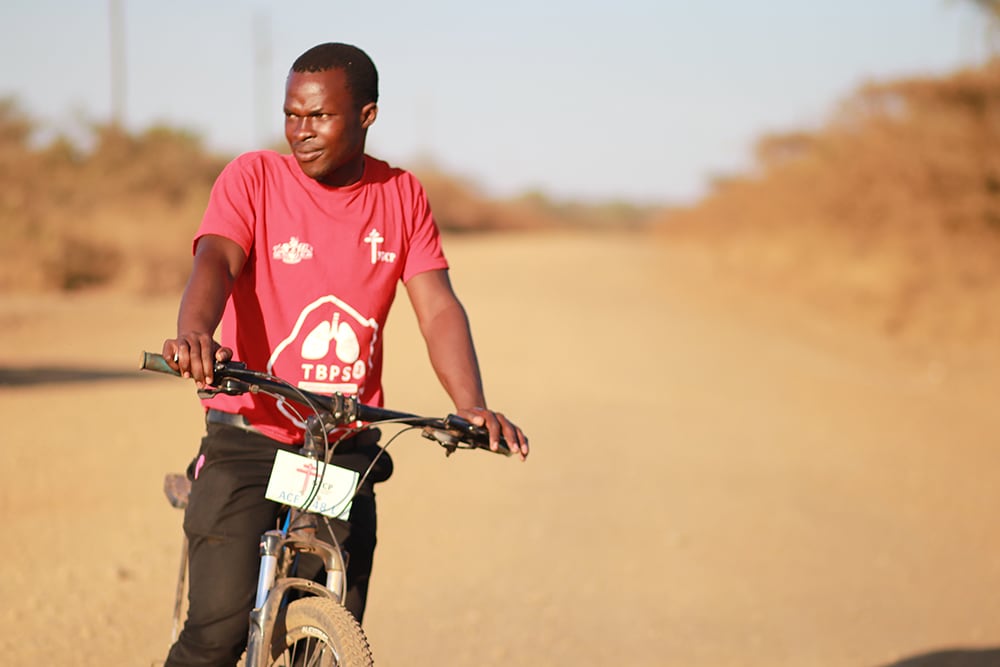 Man in red shirt on bicycle.