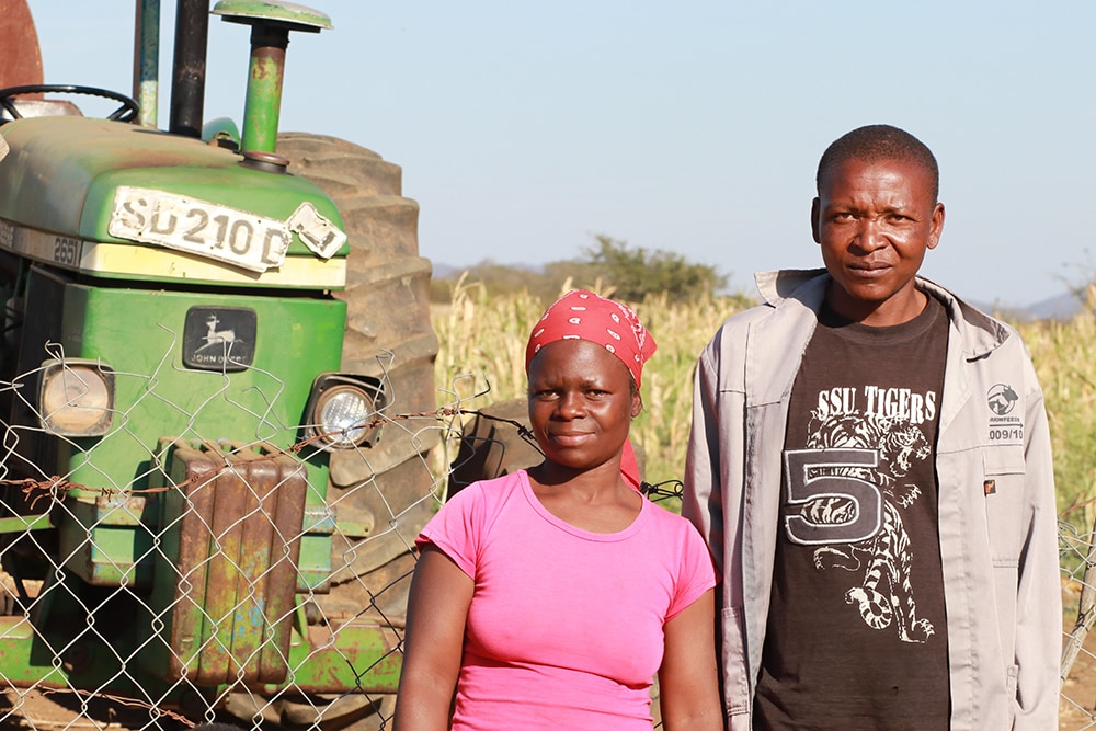Man and woman in front of tractor.