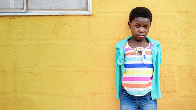 11-year-old Gugu alive and healthy standing in front of a yellow wall