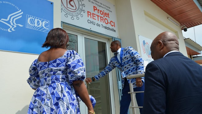 Dr. John Nkengasong and two health officials open the door to walk into the Retro-CI lab.