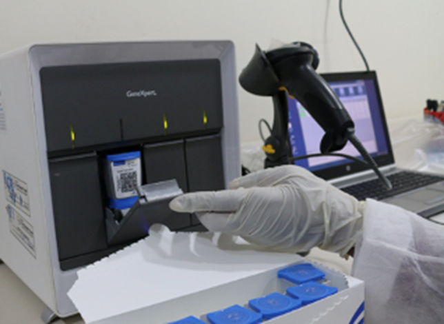 A microbiologist inserts sample into an Xpert machine to diagnose DR-TB.