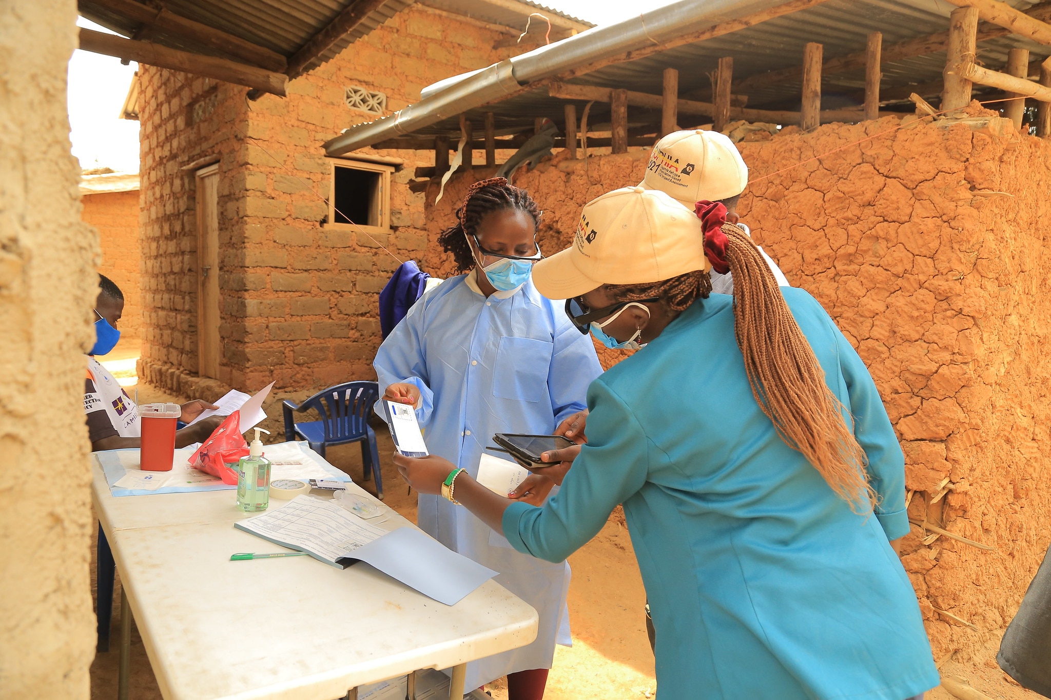 Three public health workers reviewing a document in a Uganda community.
