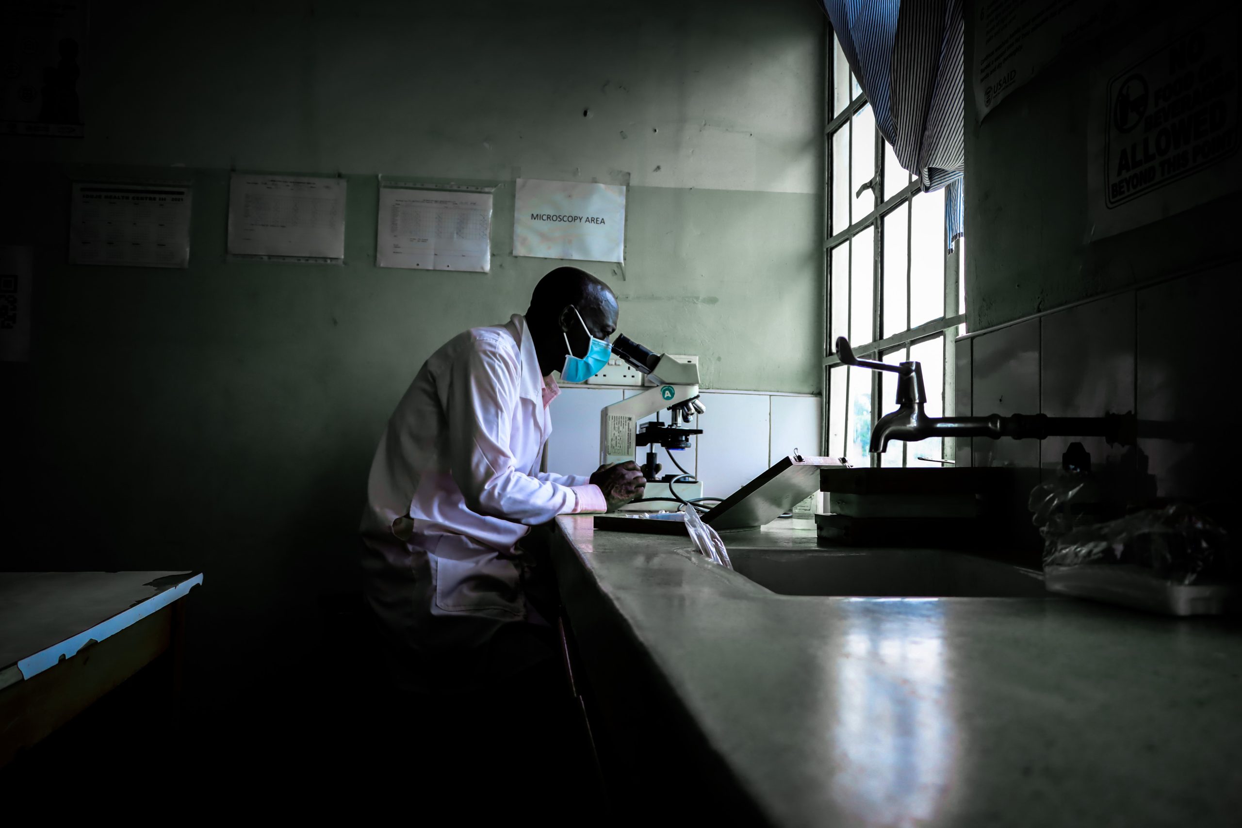 Man in laboratory looks through a microscope.