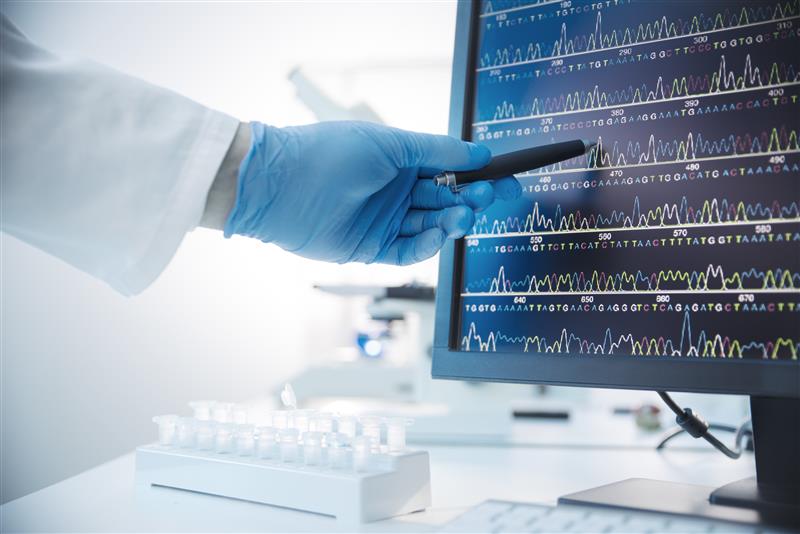 Hand with glove pointing at monitor with sequence data.