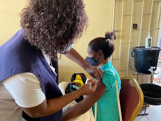 A health care worker providing a vaccine to a woman at Chainda Clinic.