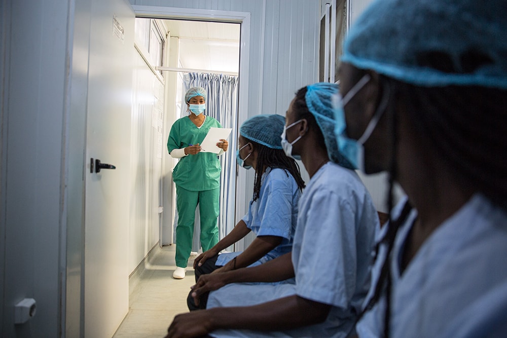 Three men wait to enter a surgical room to receive VMMC.