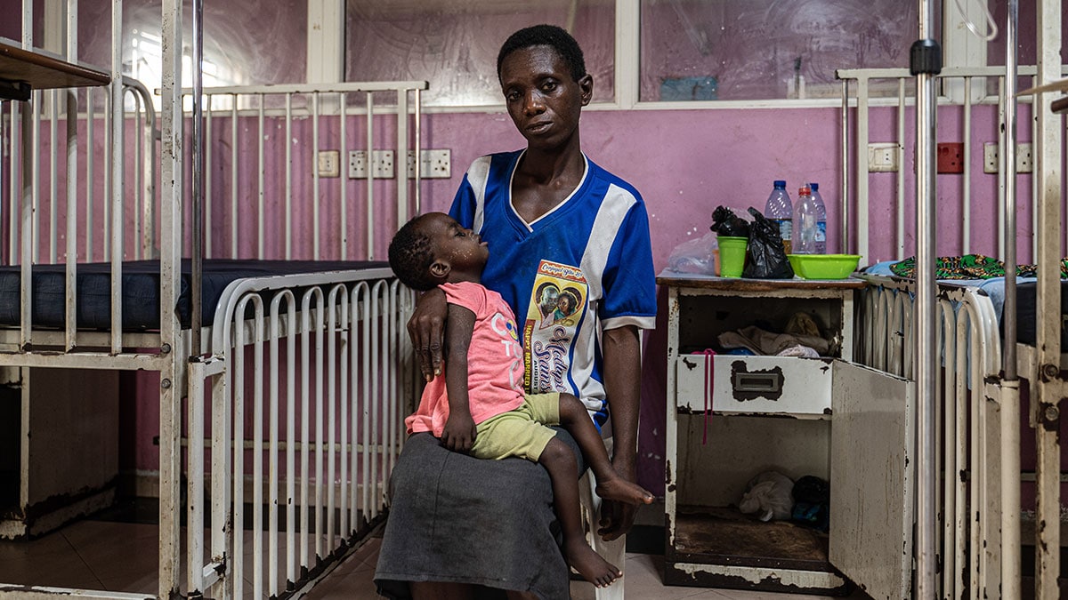 A mother cradles her daughter in a clinic.