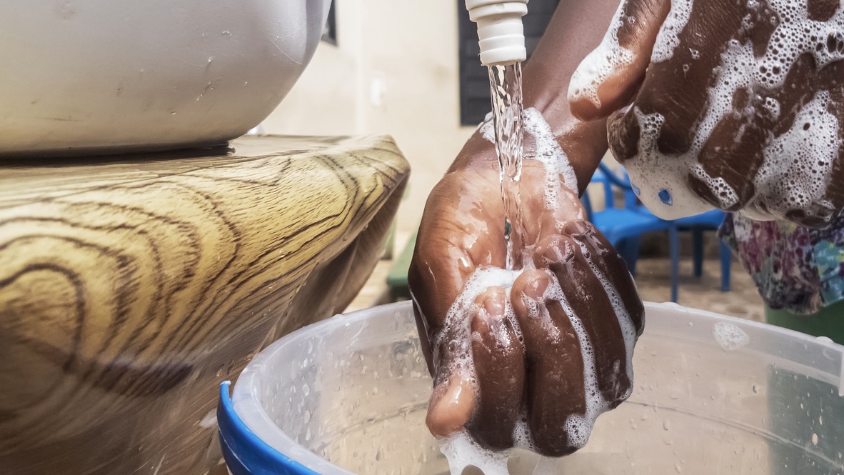 Closeup of a woman's soapy hands being rinsed under a faucet