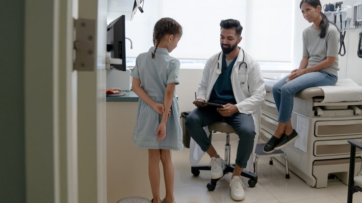 Doctor sees pediatric patient while mother observes