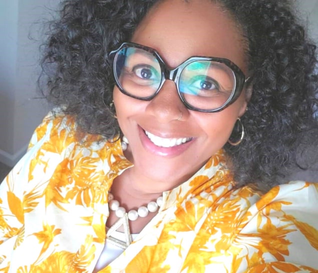 Melinda Jordan in a yellow blouse wearing a pair of glasses from her personal collection.