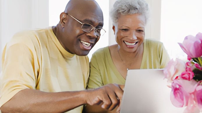 Two older adults looking at a computer.