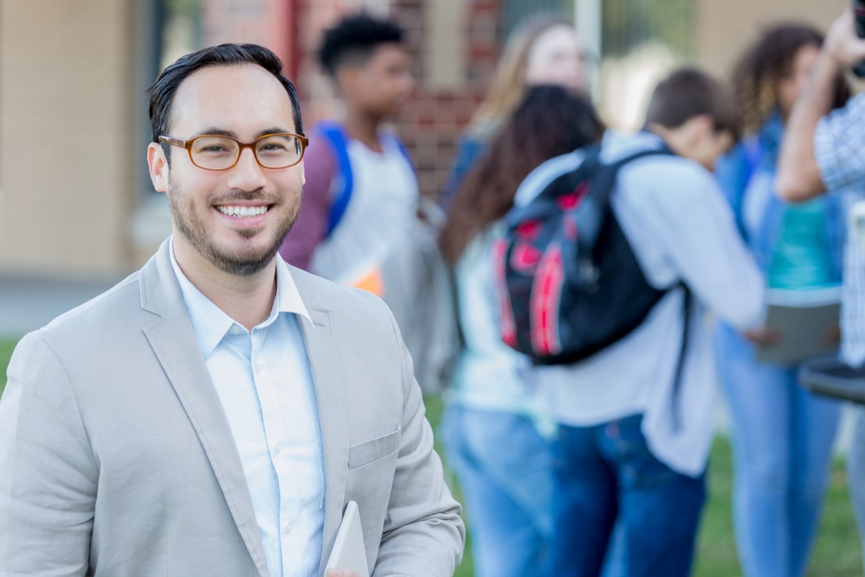 Confident teacher standing outside of school.