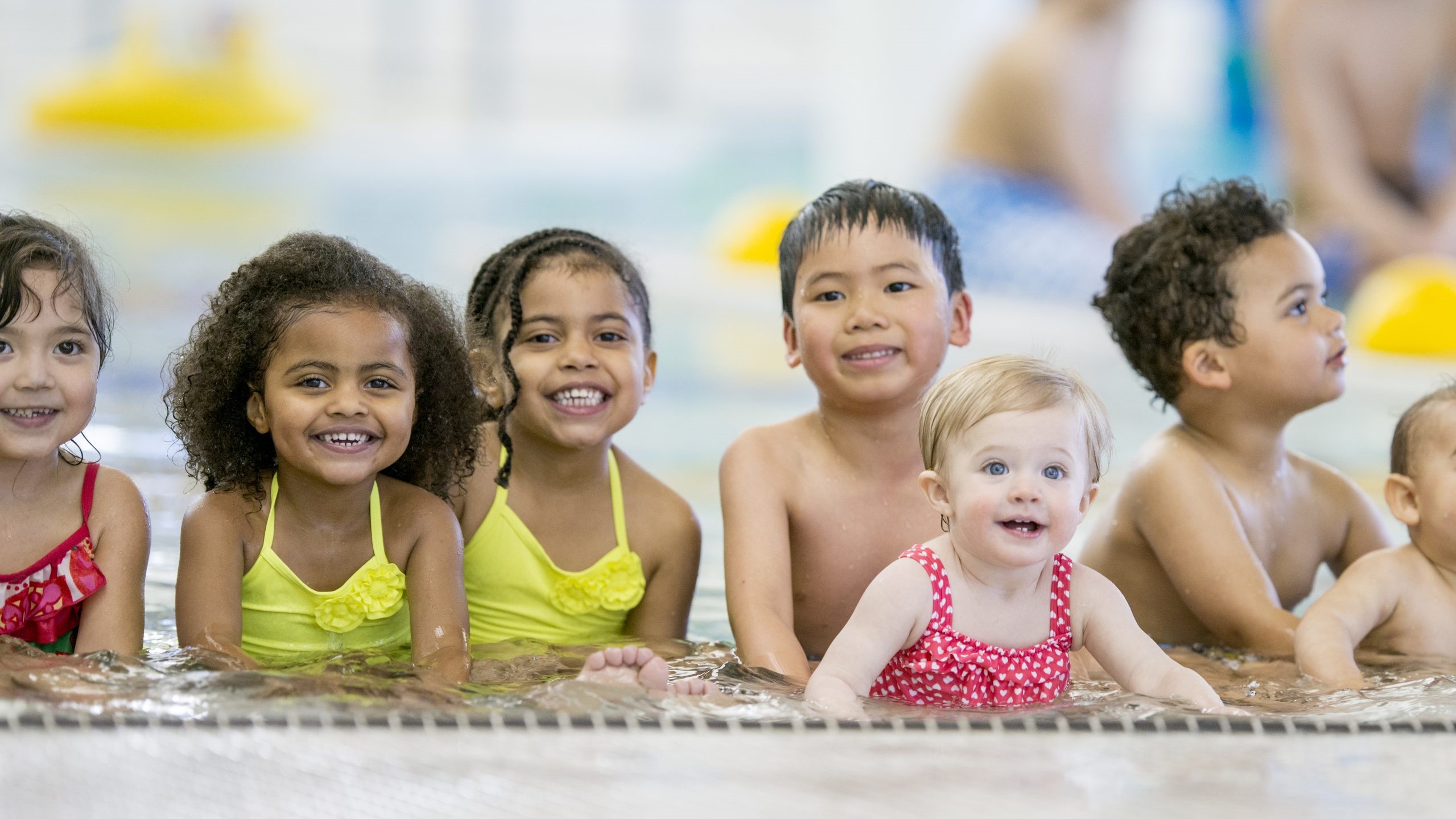 Niños pequeños en el extremo poco profundo de la piscina.