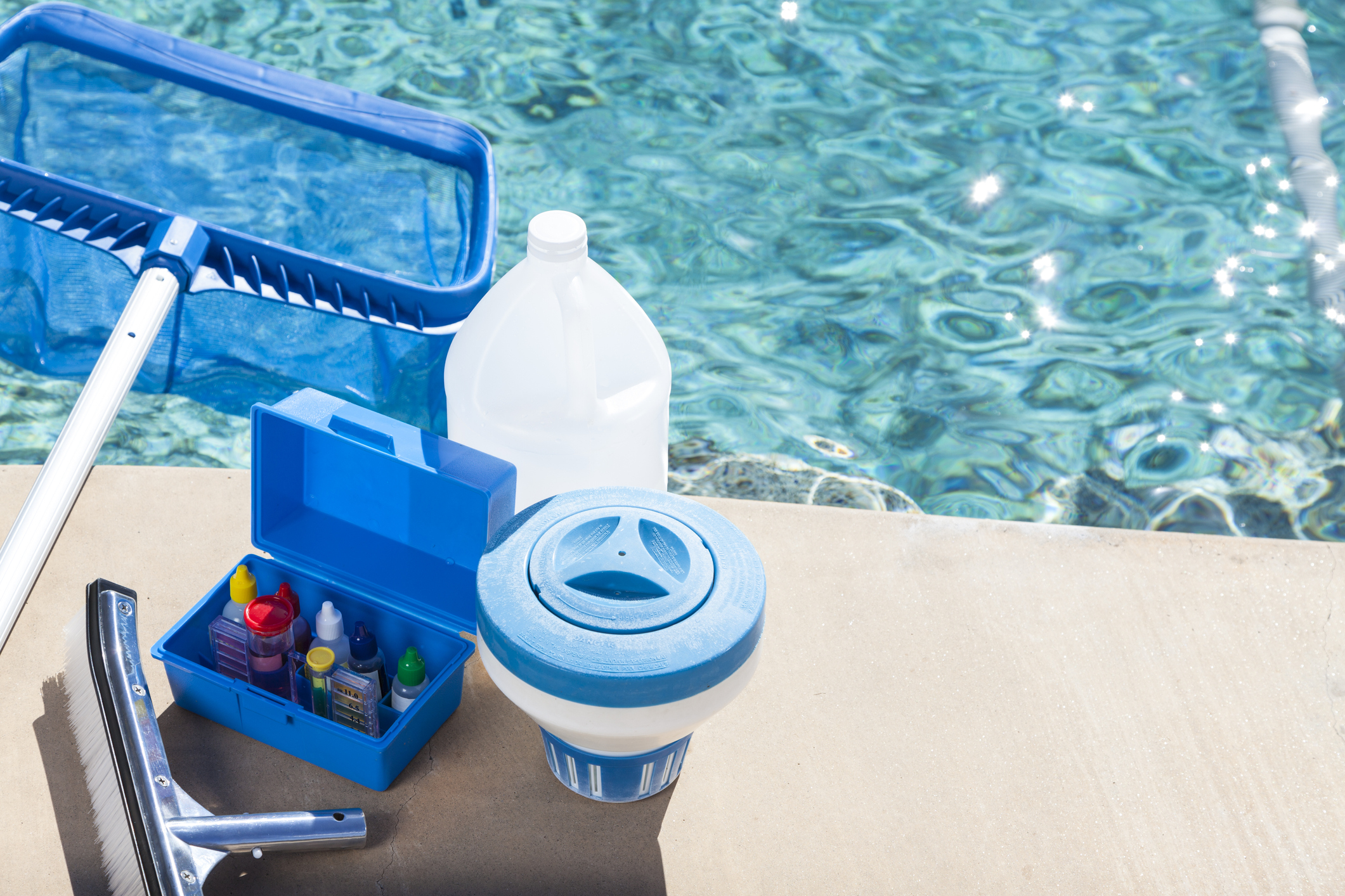 Productos químicos para piscinas al lado de una piscina.