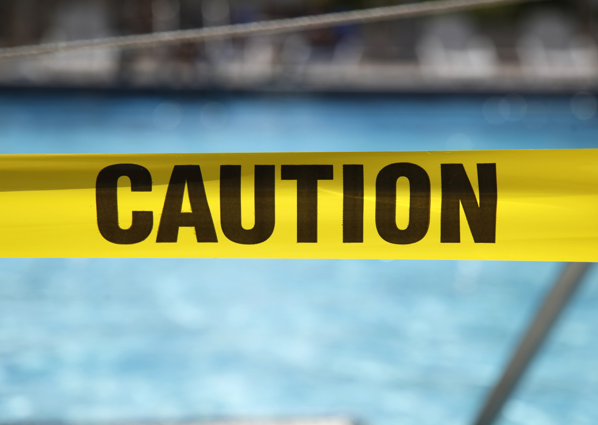 Cinta de precaución en frente de una piscina.