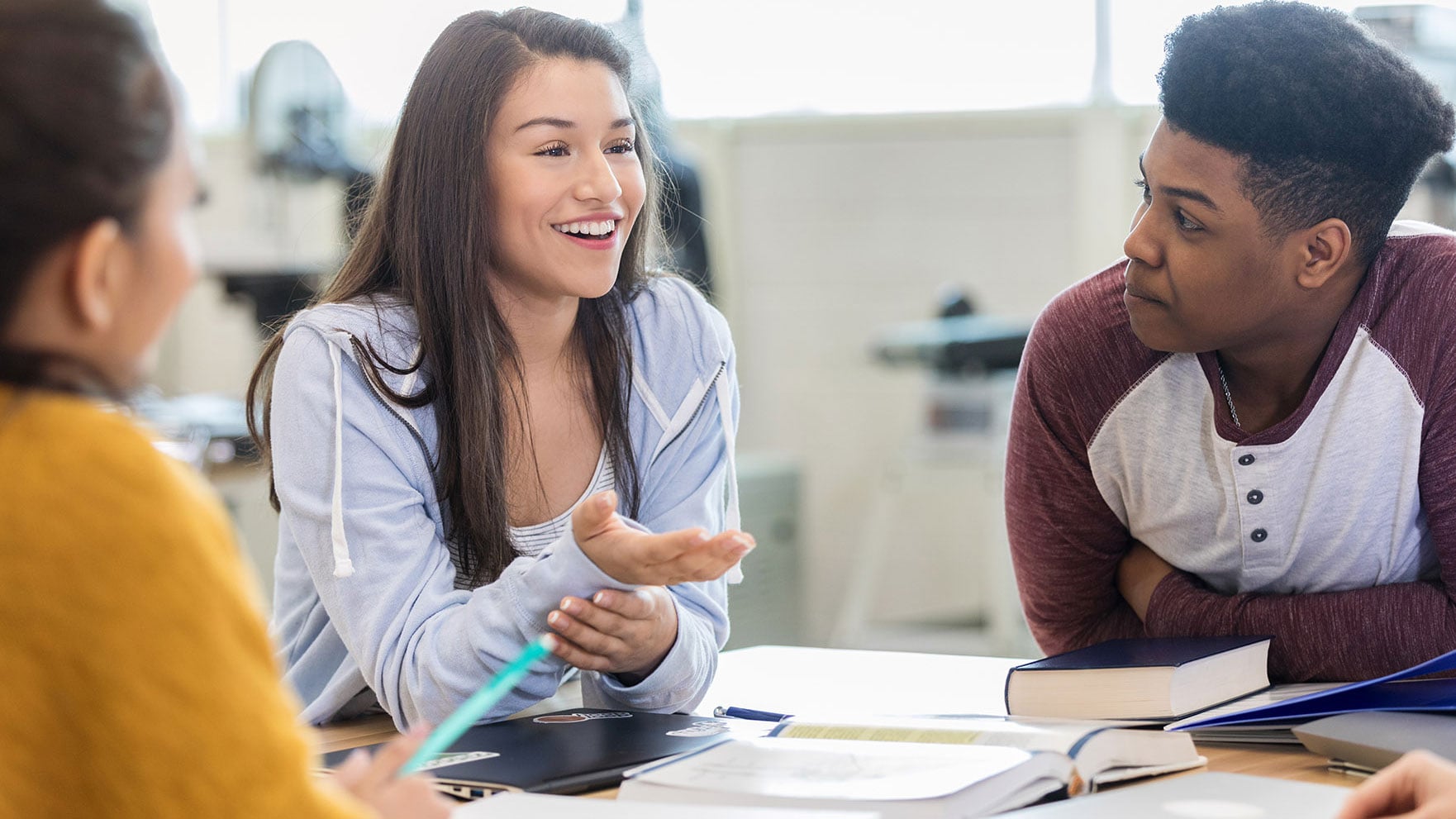 Three students sitting around a table and talking.