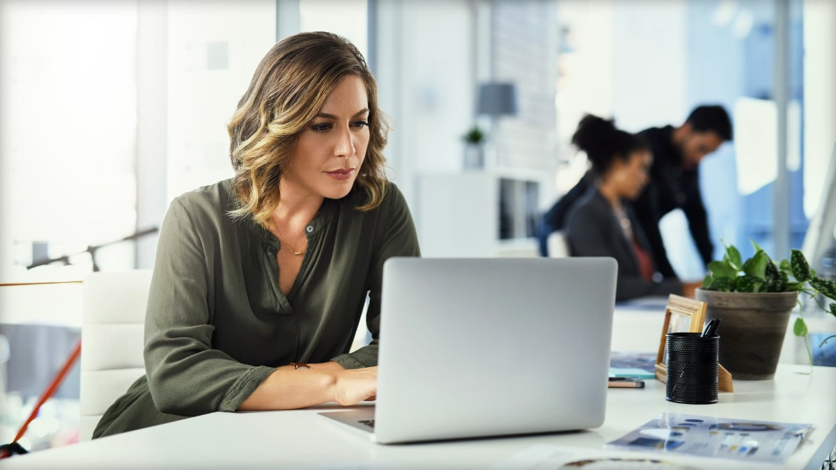 Adult sitting at a desk looking at her laptop.