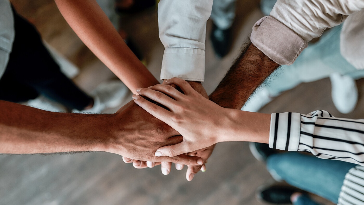 Close-up of five people's hands placed on top of one another.