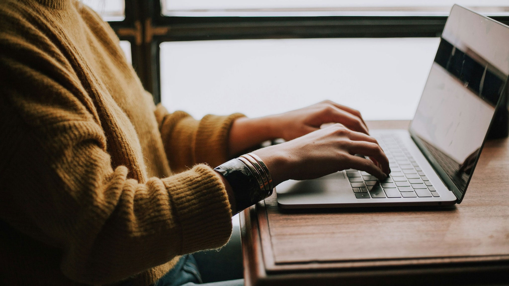 A person's hands typing grant information on a laptop.