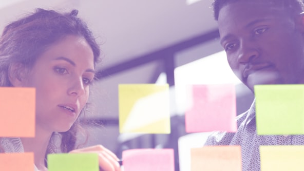 A female teacher and male teacher looking at and organizing Post-it notes.