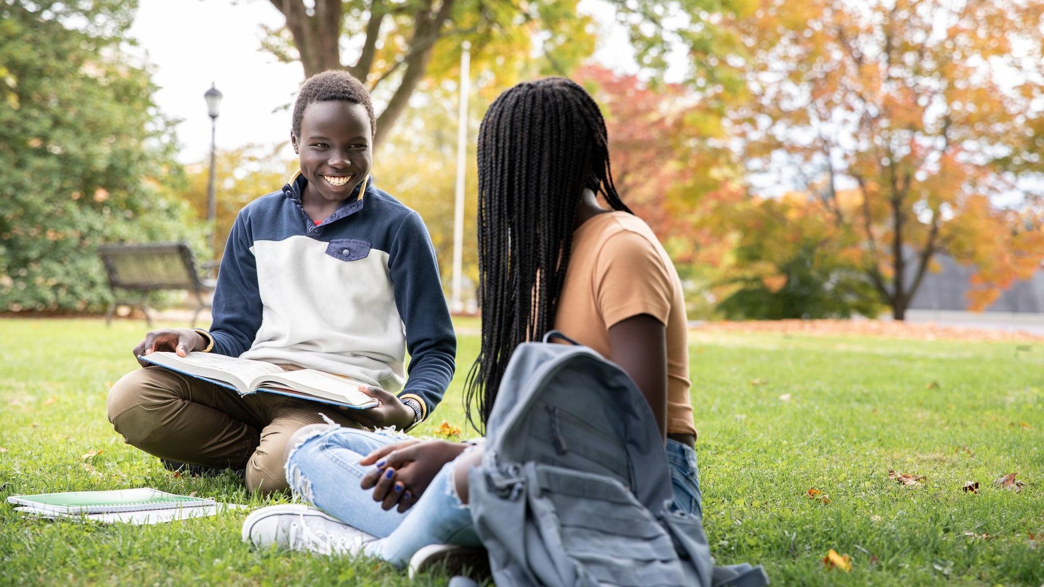 A male and female students sitting and talking outside school building.