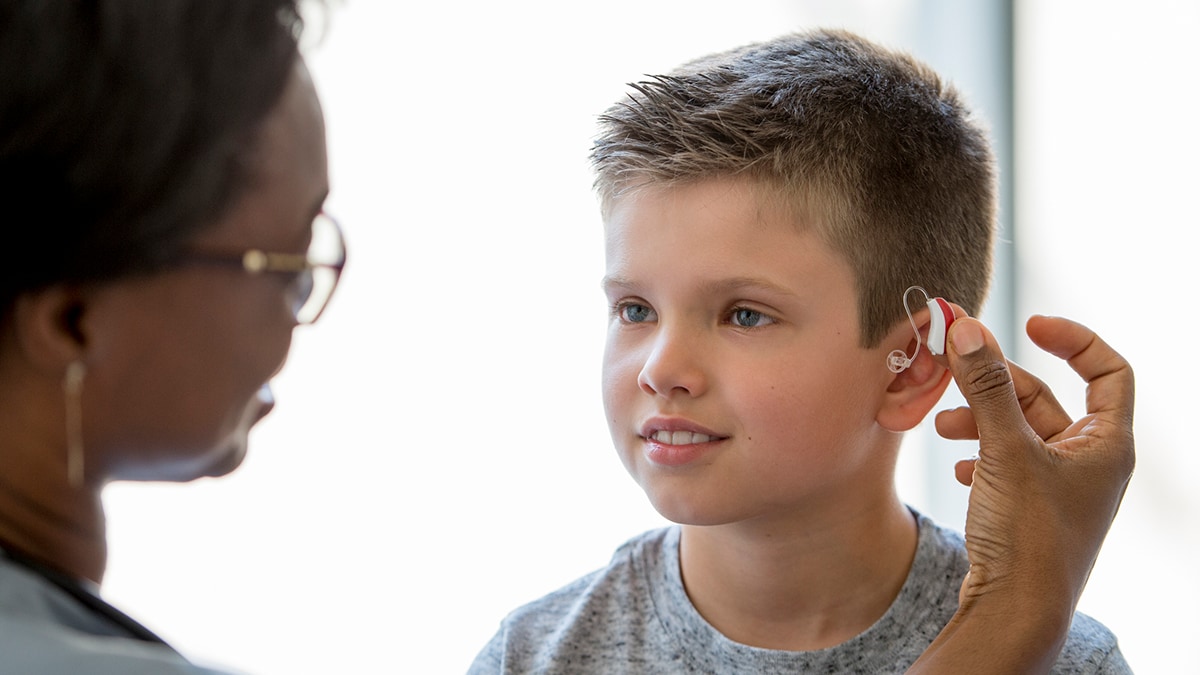 Young boy being fit for a hearing aid by doctor