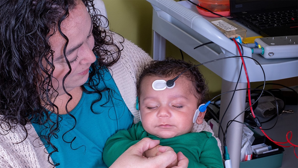 Mom holding sleeping baby during hearing screening