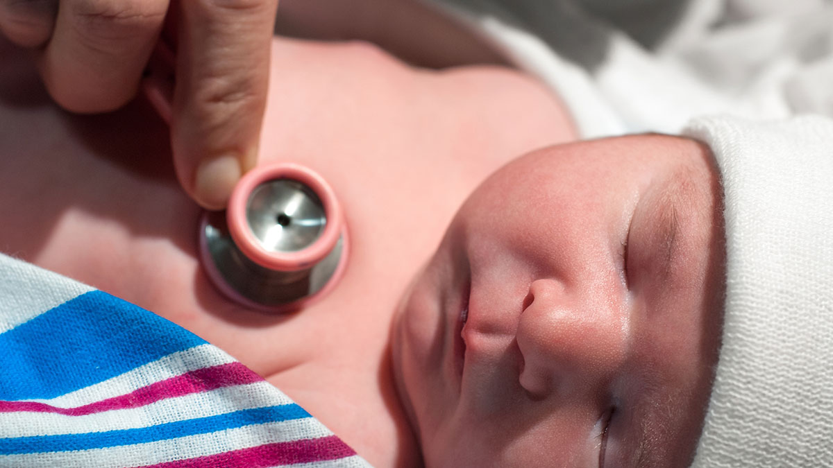 A medical professional is listening to a newborn's heart