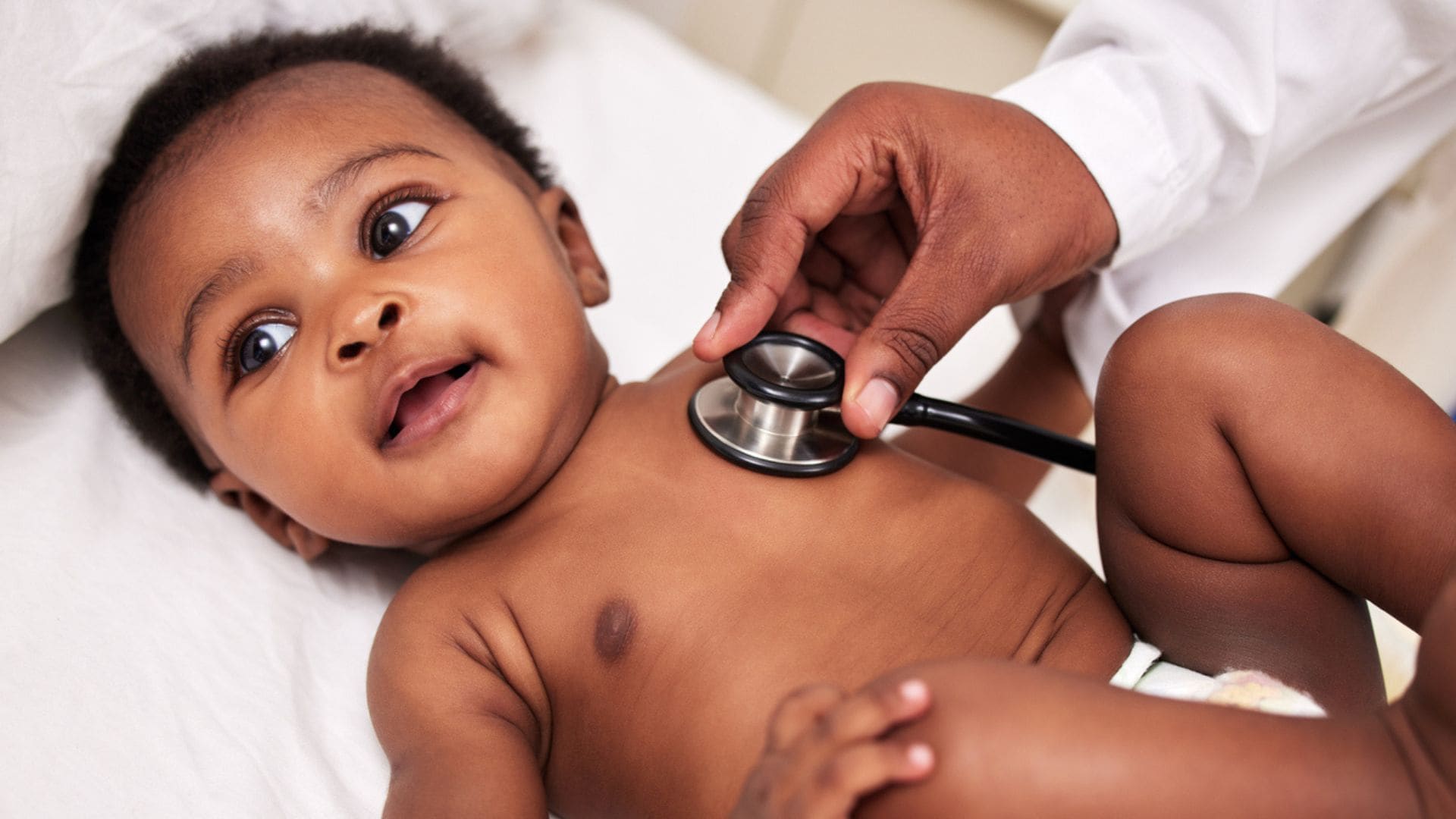 A doctor has a stethoscope on a babies chest