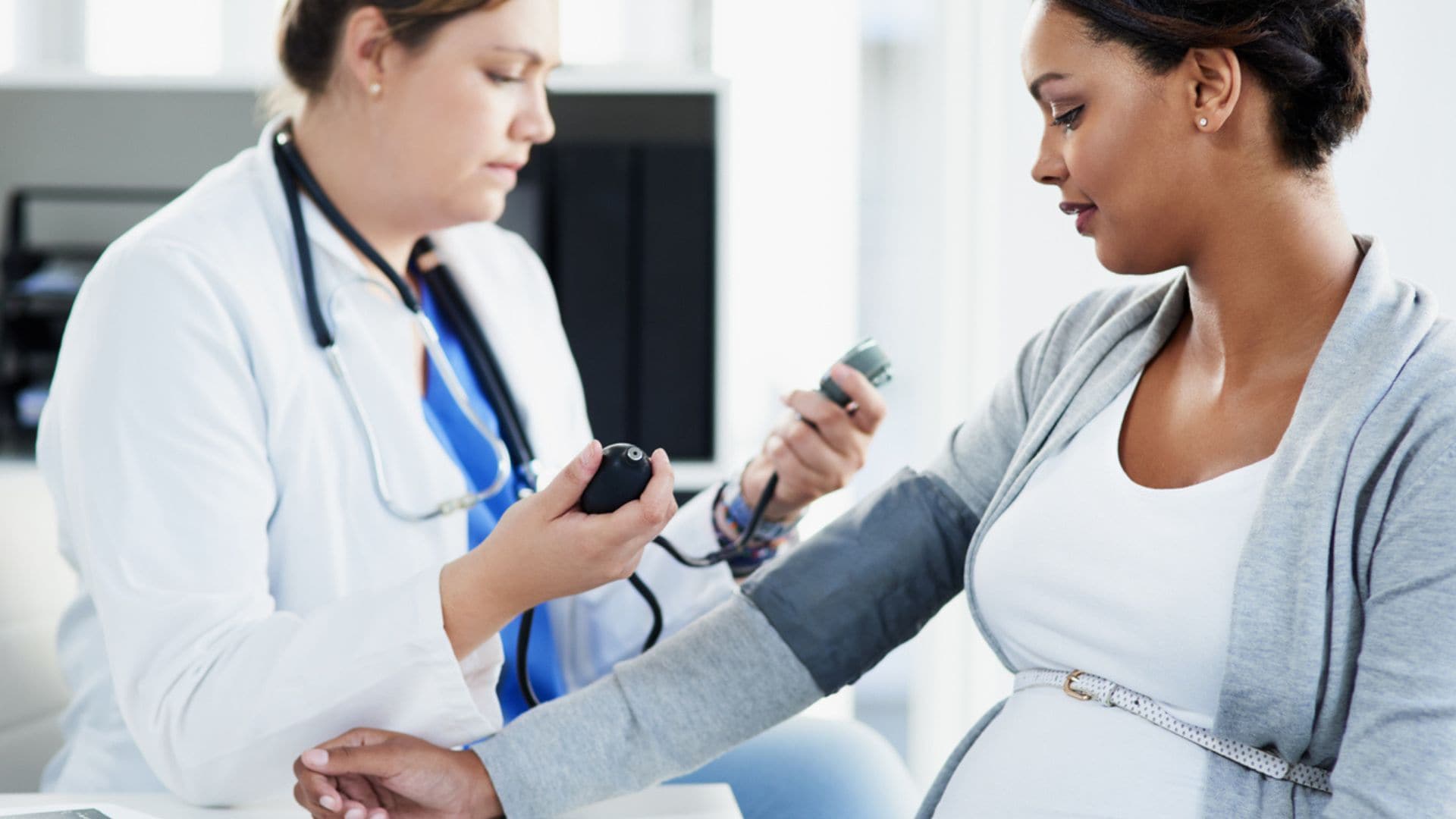 Doctor taking pregnant women's blood pressure