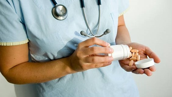 Nurse pouring out a bottle of pills into their hand