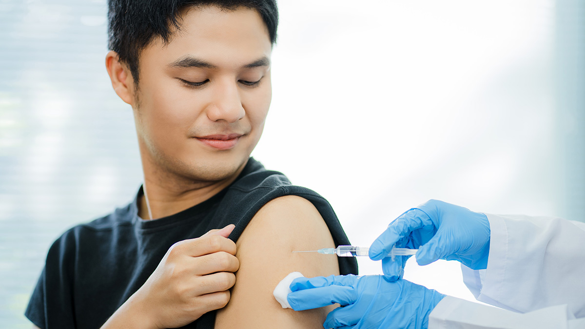 一名医生在一名男子的肩膀上注射疫苗