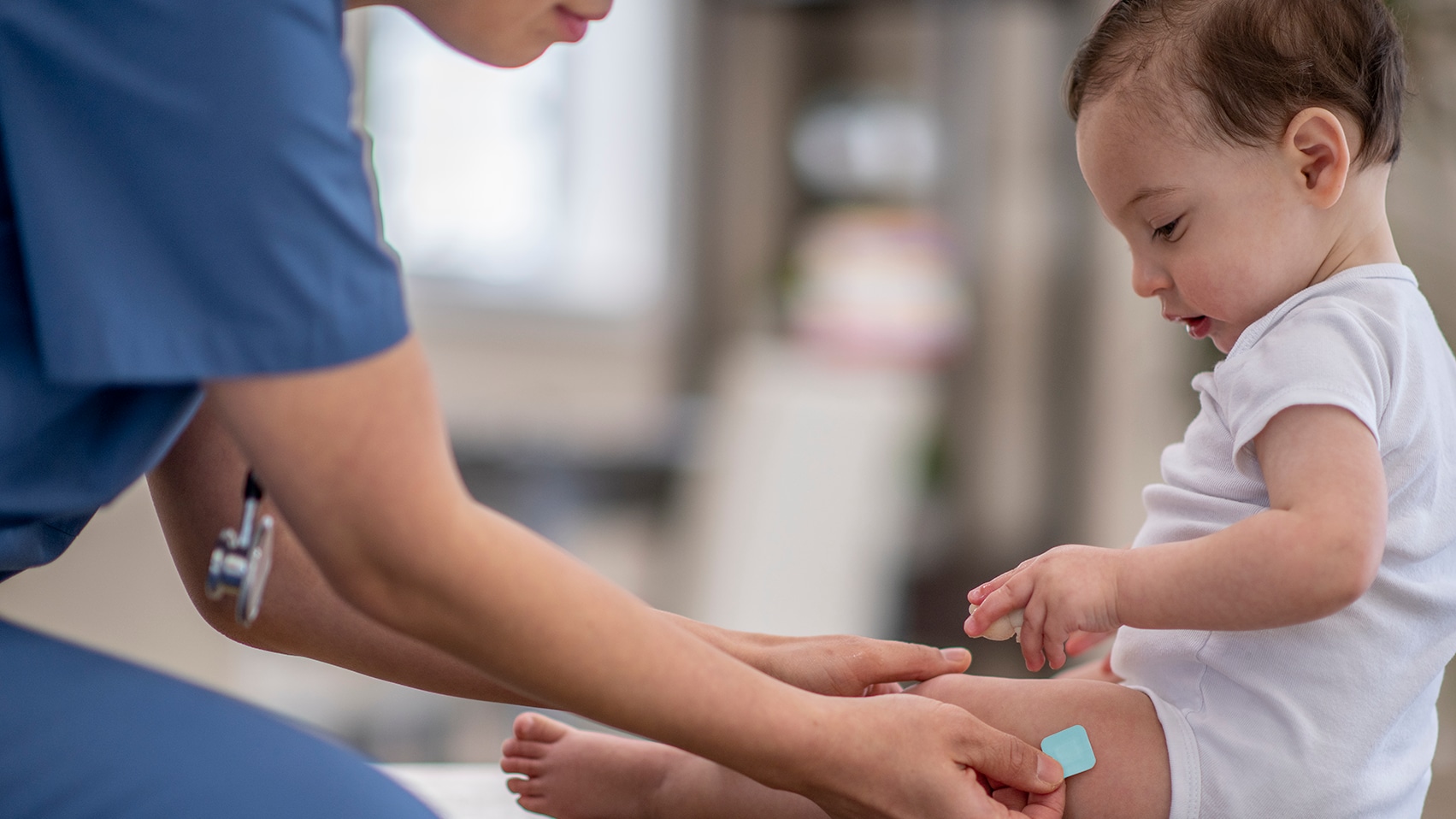 A healthcare provider places a Band-Aid on baby's thigh.