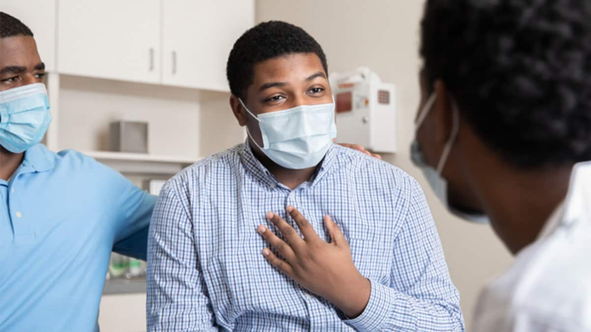 A masked patient receives advice from doctor.