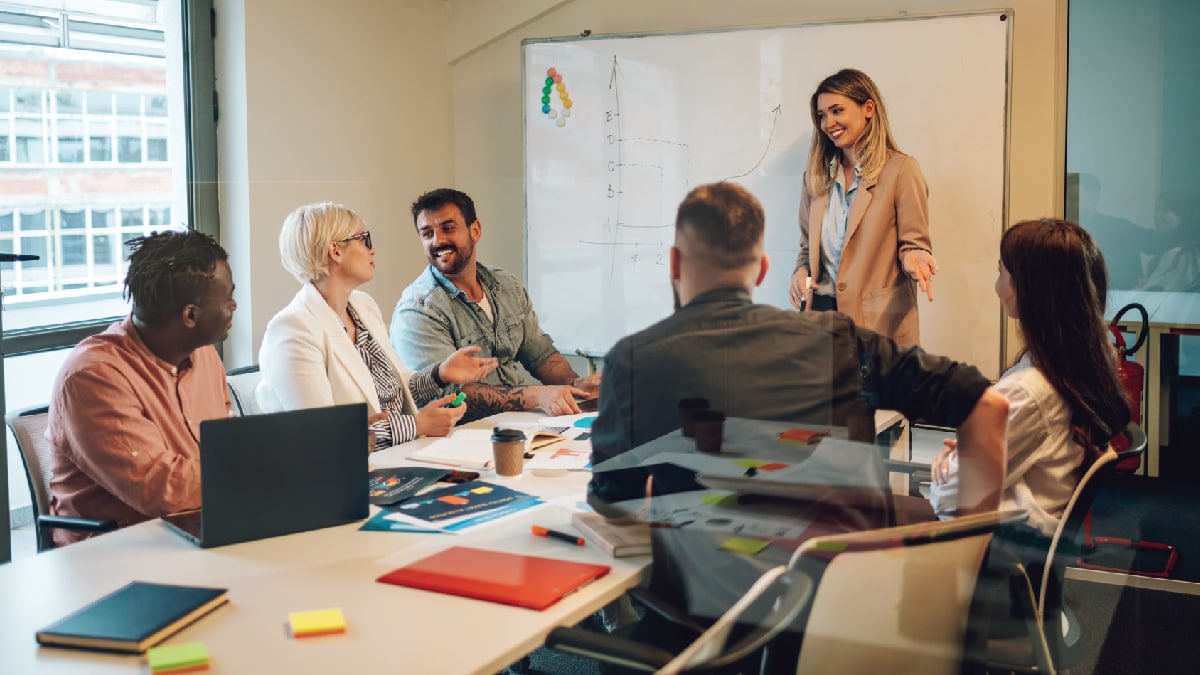 Group of people in training room smiling at and talking to each other.