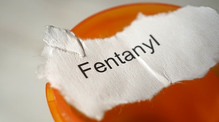 A pill bottle and a scap of paper with the word "Fentanyl" on it