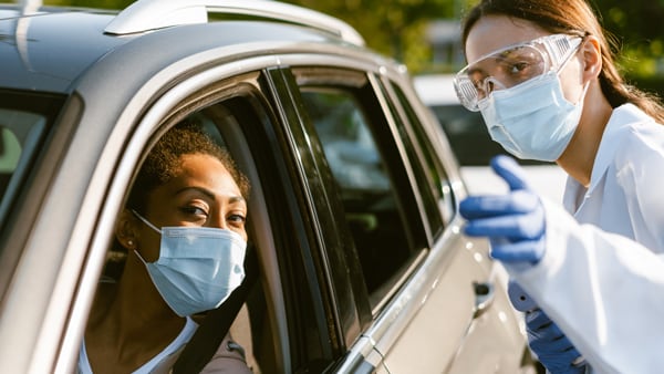 Young woman wearing PPE driving up to COVID testing site