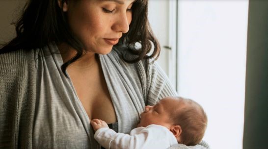 Female caregiver holding a sleeping baby.