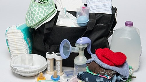 A diaper bag filled with supplies for an infant or young child such as ready-to-feed formula, clothing and water.