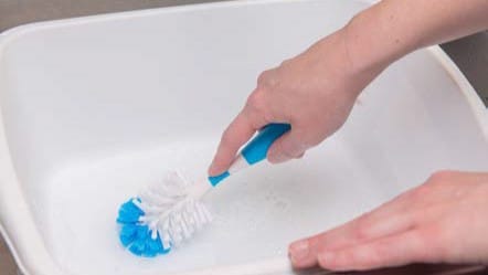 A person cleaning a wash basin.