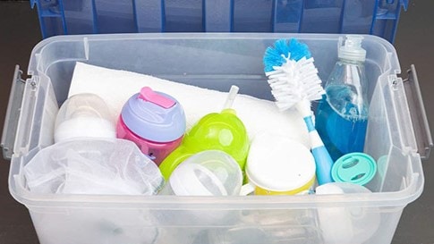 A container full of cleaning supplies and infant feeding items.