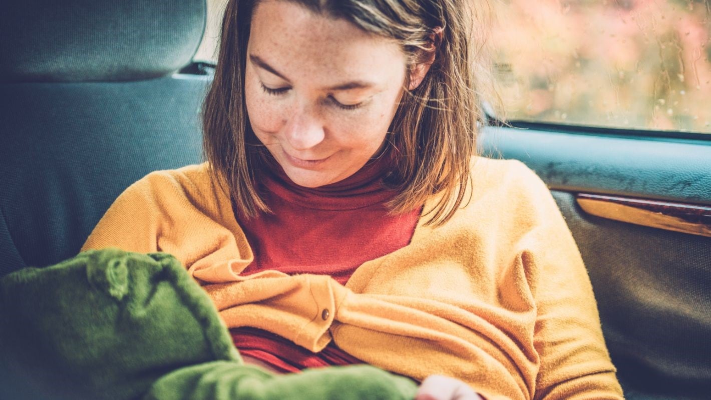 Mother breastfeeding her baby in a car.