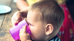 An older infant drinking from a cup.