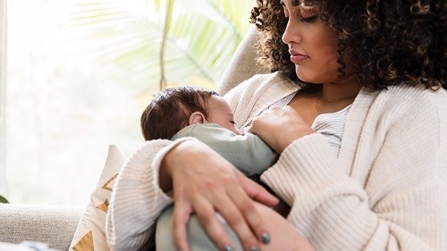 New mom watches as baby breastfeeds