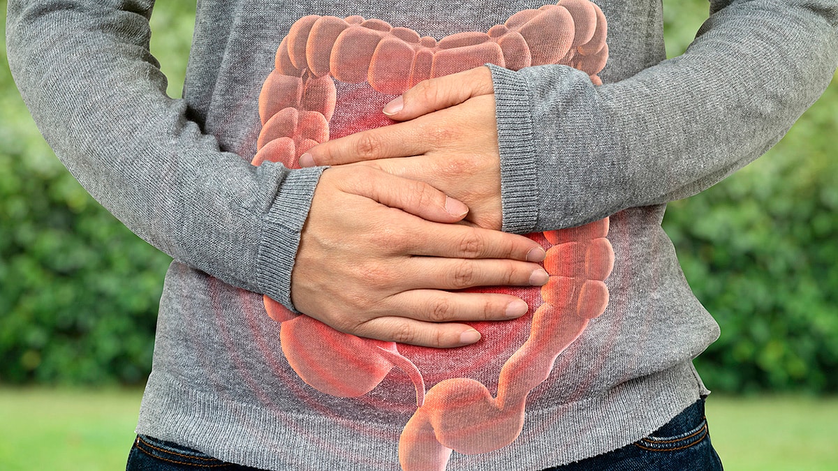 A man outside holds hands on stomach with an illustration of bowels.