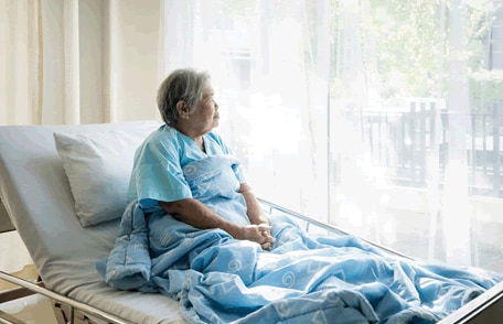 Woman in a hospital bed looking out of a window