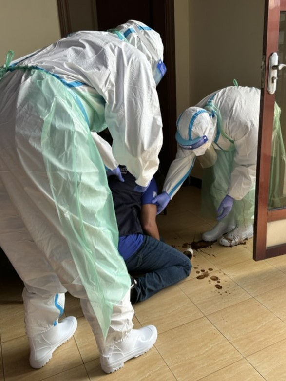 Healthcare workers in personal protective equipment care for a patient.